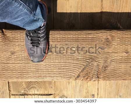 Right foot step on wooden part by walking in sunny day.