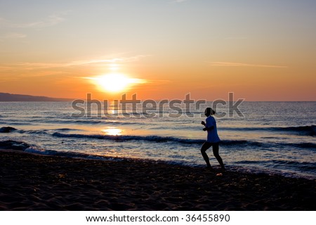 Female runner silhouette  with a soft pastel sunset sky and sea as backdrop