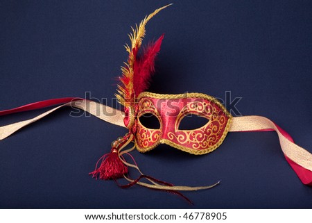 red and gold feathered mask on a dark background