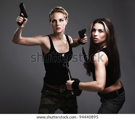 two sexy women with gun and dagger on gray