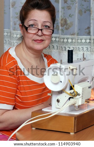 old woman sews clothes in-home
