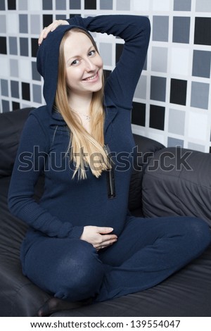 Beautiful blonde pregnant woman sitting inside home