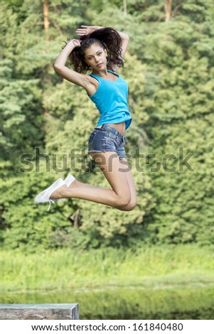 Happy young woman jumping for joy in a summer park