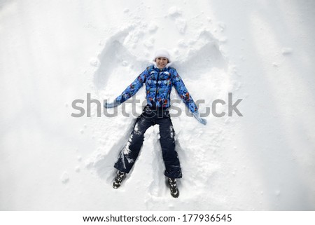 Young happy woman kidding on snow in winter day