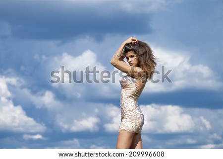 Young beautiful girl posing on blue sky background