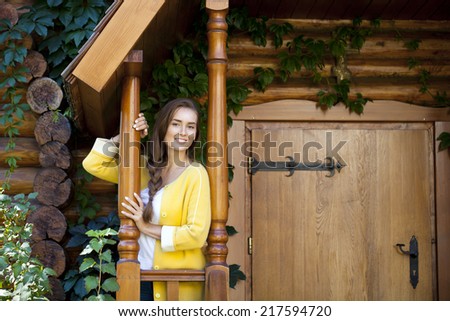 Beautiful young woman standing on the porch of a wooden house