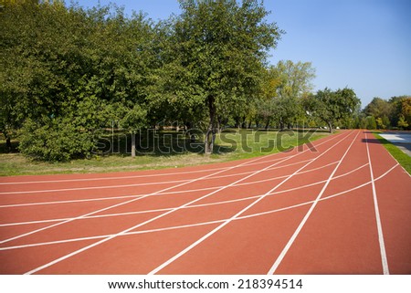 Red running tracks in sport stadium in autumn park