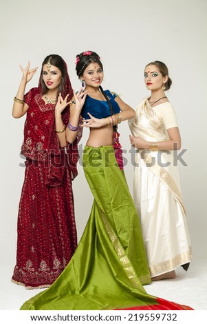 Three beautiful young women in indian dress on gray background