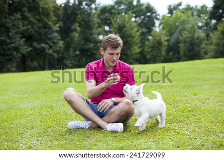 Young man playing with his dog in the summer park