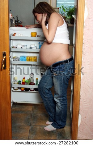 The pregnant woman near a refrigerator with meal