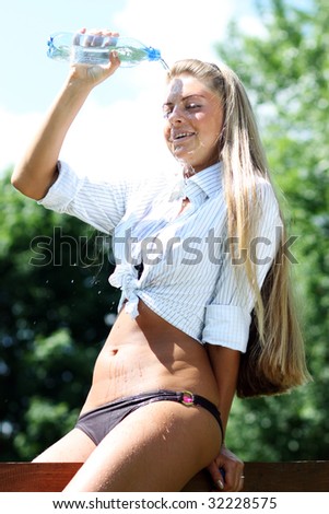 young woman pours over itself water from a bottle