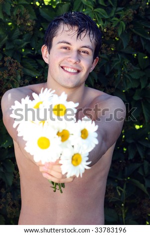 young beautiful guy with a bouquet of field flowers - camomiles