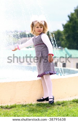 Small girl playing near fountain in park