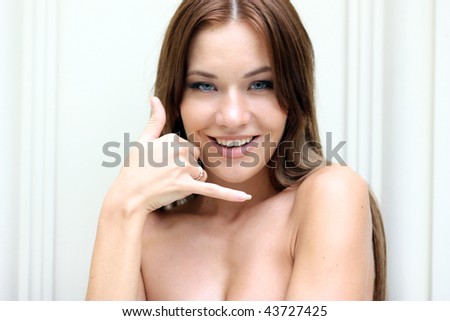 Closeup portrait of a funny woman making call-me gesture standing indoors