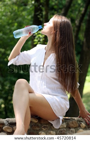 Heat. The young woman drinks mineral water