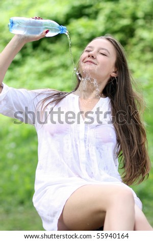Young  attractive  woman drinks mineral water  in park