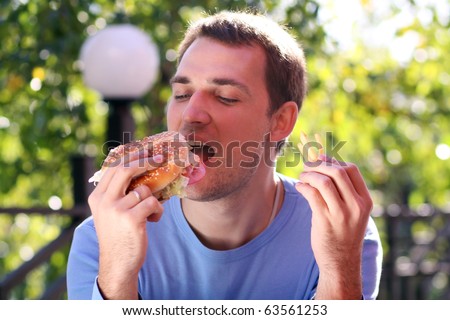 fat man eating burger. stock photo : Young man eating