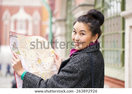 Young beautiful asian girl holding a tourist map of Moscow, Russia. The inscription on the tourist map: \