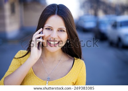 Young beautiful woman calls on his cell phone on the street