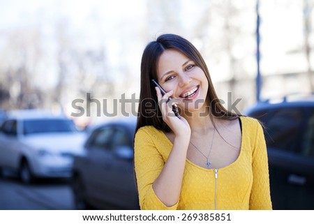 Young beautiful woman calls on his cell phone on the street