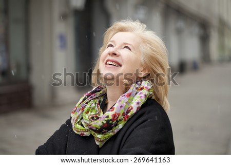 Unexpected snowfall in mid-April, happy portrait of an elderly woman in the street