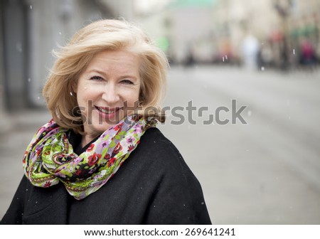 Unexpected snowfall in mid-April, happy portrait of an elderly woman in the street