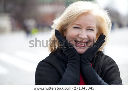 Happy portrait of an elderly blonde woman, spring on the street