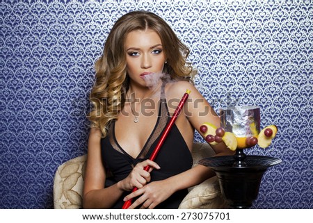 Beauty portrait of young curly blonde woman resting in the hookah room