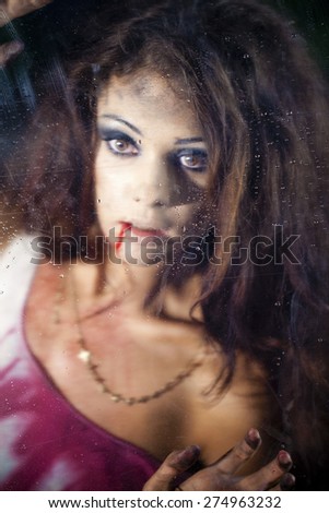 A terrible and bloody woman looking through wet glass
