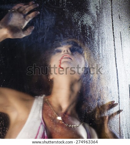 A terrible and bloody woman looking through wet glass