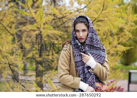 Portrait of young Italians in a beige coat and knit a scarf on her head