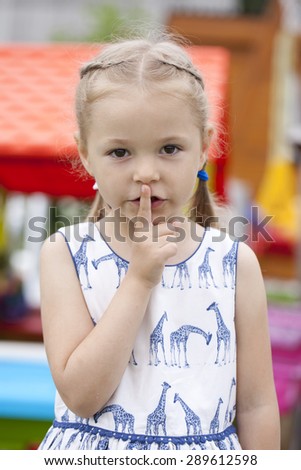 Young beautiful Little girl  has put forefinger to lips as sign of silence