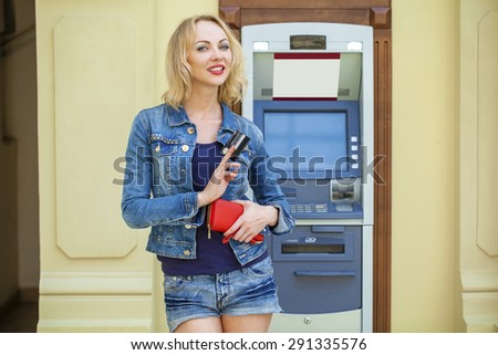 Blonde lady using an automated teller machine. Woman withdrawing money or checking account balance