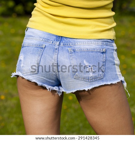Part of the body, torn blue jeans shorts for women on the background summer street