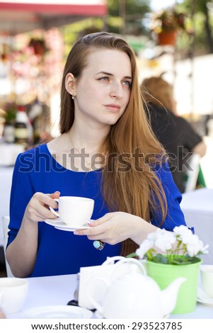 Happy Beautiful young blonde woman sitting in a coffee shop and drink tea