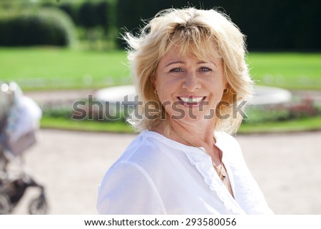 Close up portrait of serene mature woman in the summer park