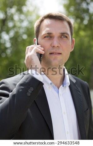 Close up, young businessman calling by phone in summer street