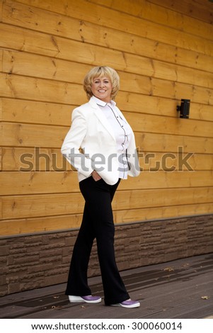 Happy elderly woman in a white jacket on the background of wooden wall