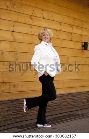 Happy elderly woman in a white jacket on the background of wooden wall