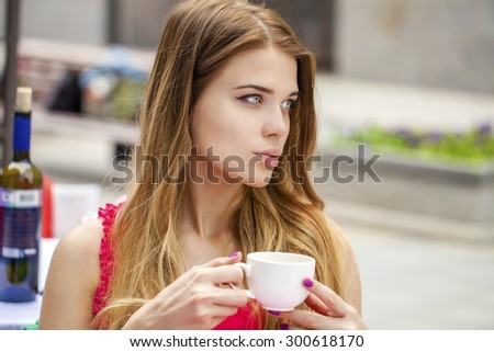 Young beautiful blonde girl sitting in a summer restaurant