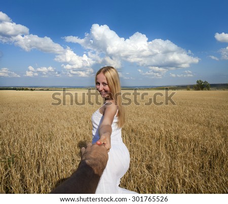 Follow me, Beautiful sexy young woman holds the hand of a man in a wheat field