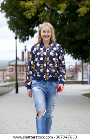 Full length, walking happy blonde woman in autumn park