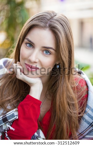 Portrait of a beautiful young woman sitting in a cafe on the street