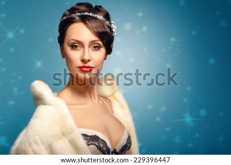 Beautiful glamor girl in a white fur coat with red lips and a beautiful decollete