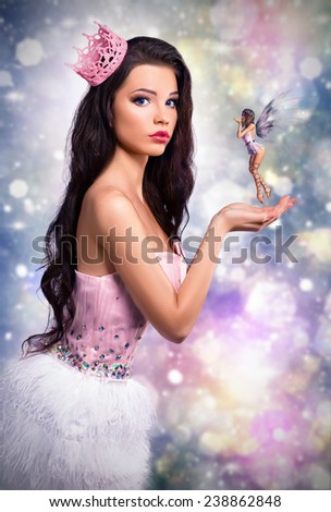 girl dressed as a princess fairy holds in his hands. fantastic brunette doll on a colorful background, close elf flies