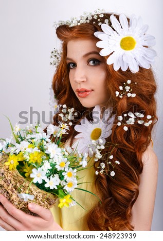 red-haired girl with daisies in her hair holding a bouquet of daisies