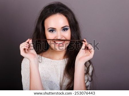 cheerful brunette with long hair holds a lock on his upper lip like a mustache.playing with hair like mustache beautiful brunette.  closeup portrait