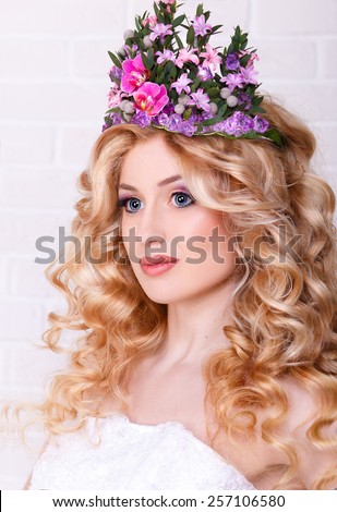 beauty portrait of a blonde with perfect makeup and a crown of flowers on her head.curly-haired blonde with flowers in her hair.Isolated on white