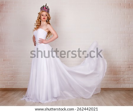 Bride in flying wedding dress in the studio on a background of a brick wall