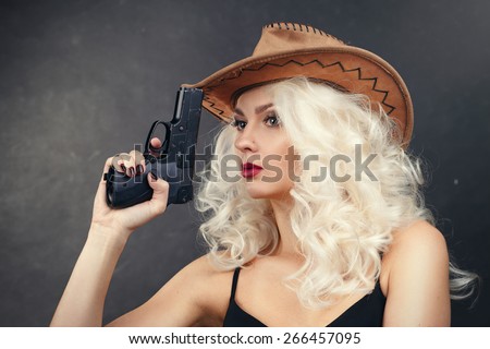 An attractive cowgirl.girl in a cowboy hat with a gun